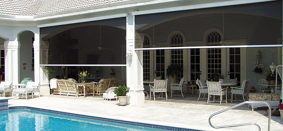 patio with chairs and motorized solair mesh vertical shade next to outdoor inground pool